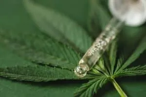 Close up view on pipette with cannabis extract on green background.