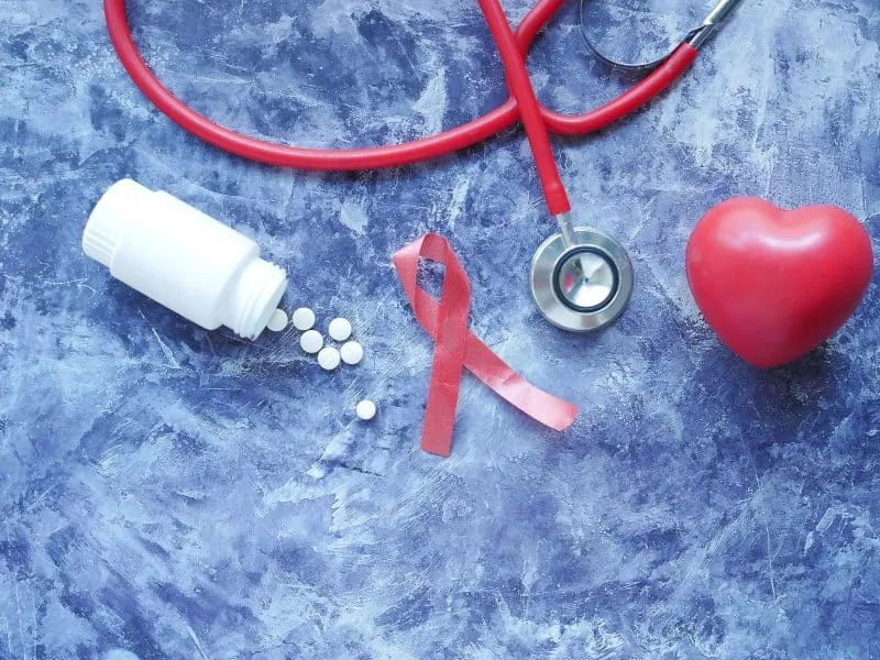 Red ribbon HIV, and stethoscope on black background..