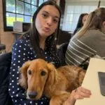 Cocapoo - basile 11 Vrouw met lang donker haar en polkadot blouse houdt een golden retriever vast.