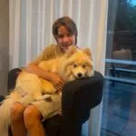 Pomsky - bulan (ulestraten, nl) 1 Young boy with a fluffy cream-colored dog sitting on a chair indoors.