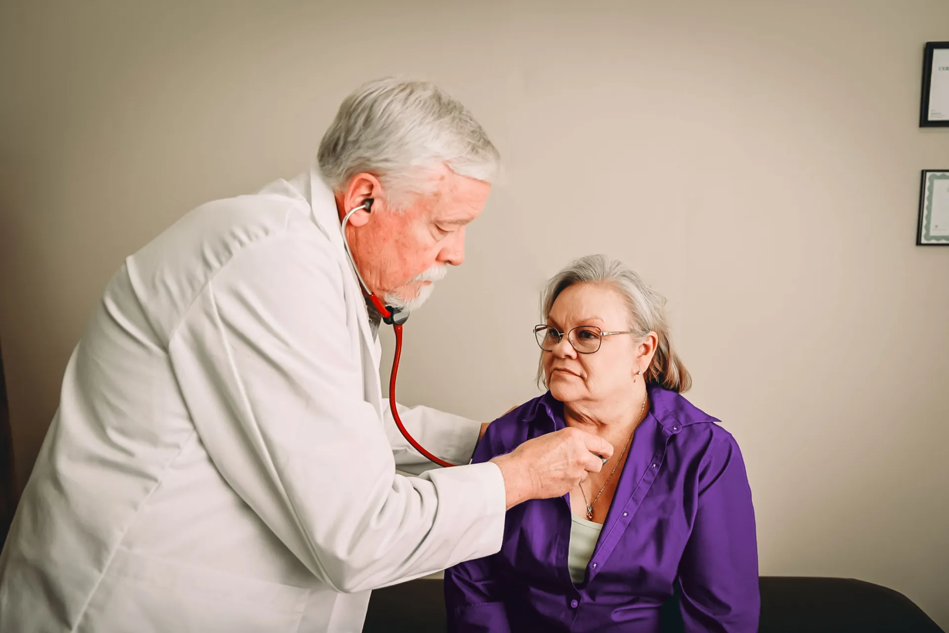 Doctor listening to older woman's heart with stethoscope